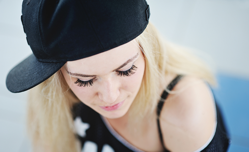 young girl with long eyelashes in a baseball cap and a T-shirt hip-hop style